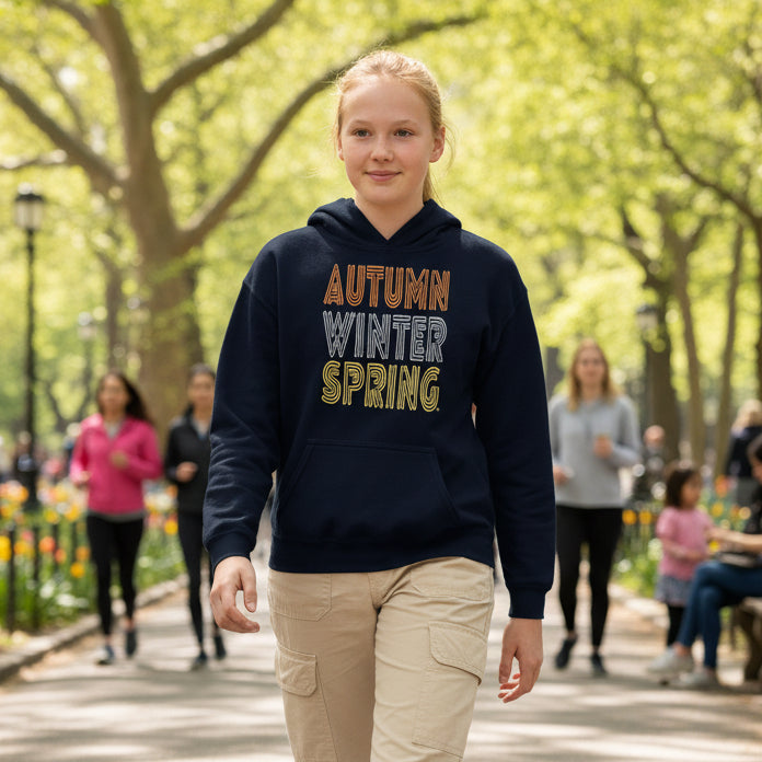 Girl walking in a city park wearing the Fall into Autumn Kid's Unisex Hoodie in Dark Blue from the APWT Kid's Shop
