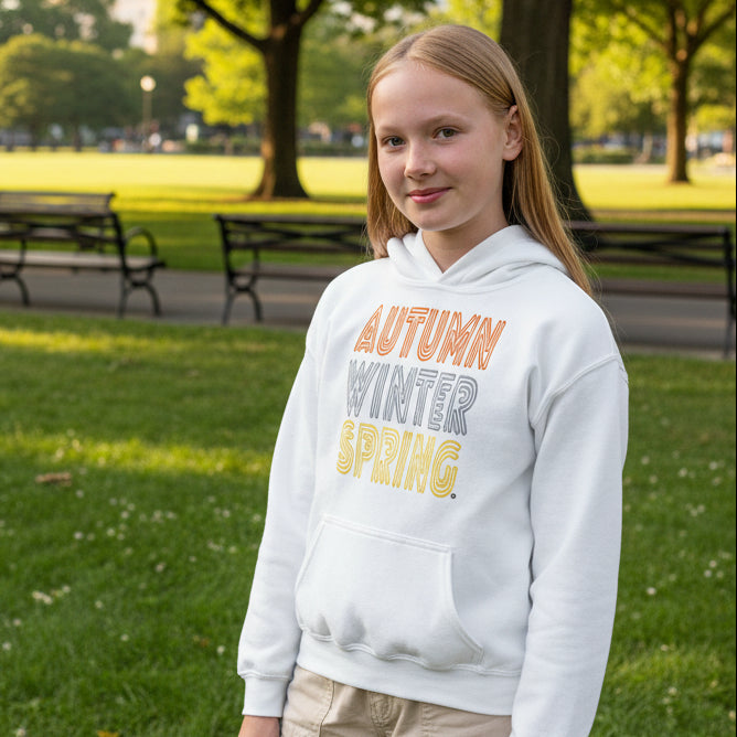 Girl standing in a city park wearing The APWT Gift Shop's Fall into Autumn Kid's Unisex Hoodie in White from the APWT Kid's Shop