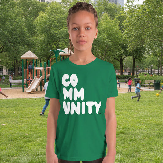 Girl wearing the APWT Gift Shop's Community Kids in Green Grass Unisex T-Shirt from the APWT Kid's Shop and the Community Collection