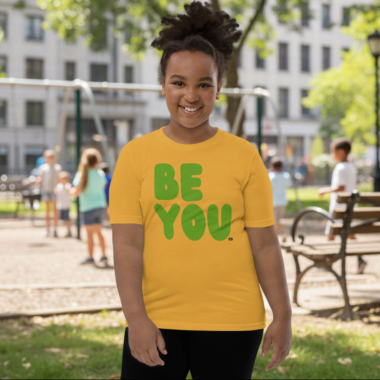 Child wearing a yellow t-shirt with 'BE YOU' text on a white background