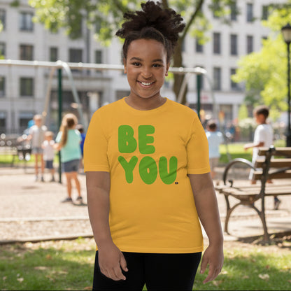Child wearing a yellow t-shirt with 'BE YOU' text on a white background